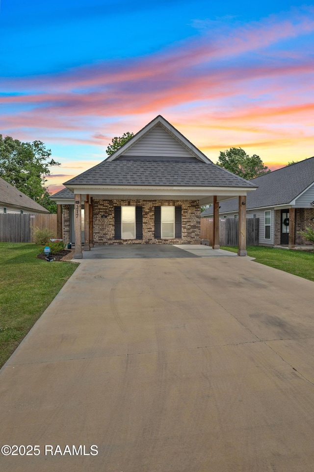view of front of home featuring roof with shingles, fence, driveway, and a front yard