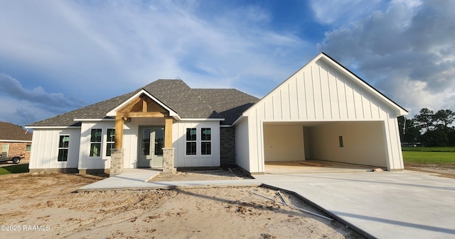 view of front of home with roof with shingles, an attached garage, board and batten siding, and concrete driveway
