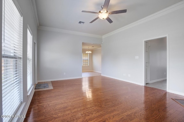 spare room featuring crown molding, ceiling fan with notable chandelier, wood finished floors, and visible vents