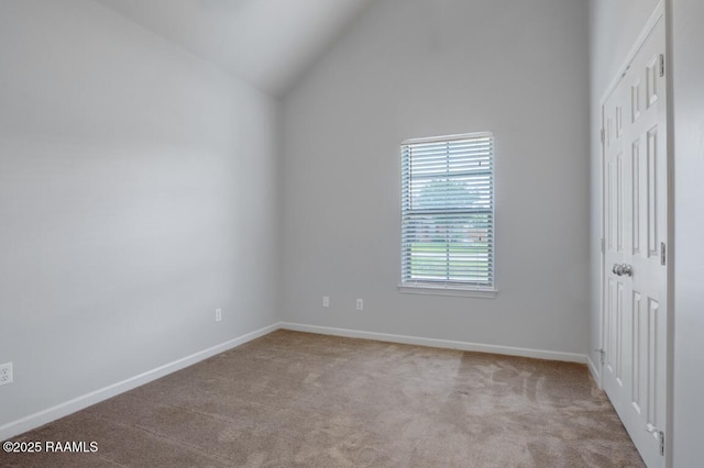 carpeted empty room with baseboards and high vaulted ceiling