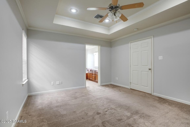 spare room with crown molding, ceiling fan, light colored carpet, a raised ceiling, and visible vents