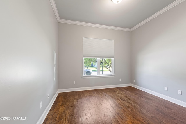 spare room featuring crown molding, dark wood-type flooring, and baseboards
