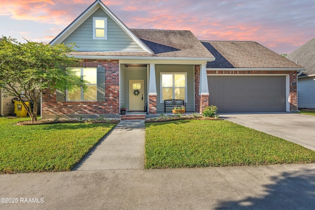 view of front facade featuring covered porch, brick siding, an attached garage, and a yard