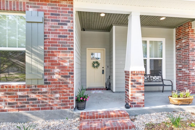 property entrance featuring covered porch and brick siding