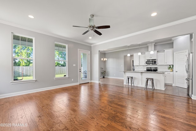 unfurnished living room featuring ceiling fan, hardwood / wood-style floors, baseboards, recessed lighting, and ornamental molding