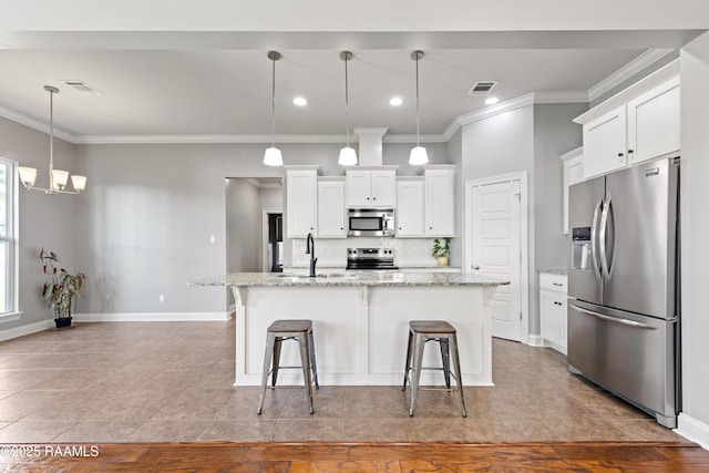 kitchen featuring appliances with stainless steel finishes, a sink, ornamental molding, tasteful backsplash, and a kitchen breakfast bar