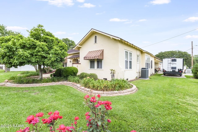 207 S Saint Valerie St, Abbeville, LA 70510 - view of side of property featuring central air condition unit, stucco siding, and a yard