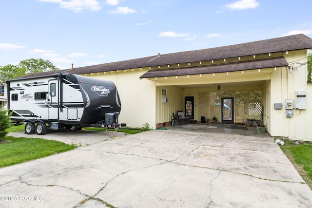 207 S Saint Valerie St, Abbeville, LA 70510 - exterior space with driveway, roof with shingles, and an attached carport