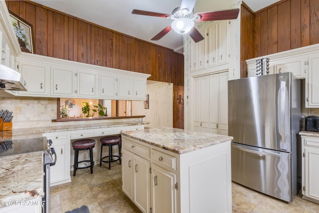 207 S Saint Valerie St, Abbeville, LA 70510 - kitchen with wooden walls, ceiling fan, appliances with stainless steel finishes, a center island, and tasteful backsplash