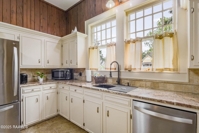 207 S Saint Valerie St, Abbeville, LA 70510 - kitchen featuring a sink, tasteful backsplash, stainless steel appliances, and wooden walls