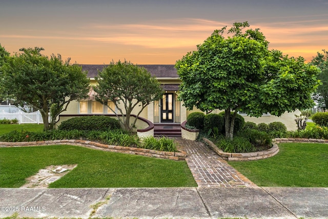 207 S Saint Valerie St, Abbeville, LA 70510 - view of front of property featuring french doors, a yard, and stucco siding
