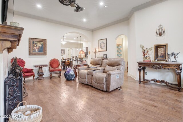 living room with arched walkways, wood finished floors, ornamental molding, recessed lighting, and baseboards