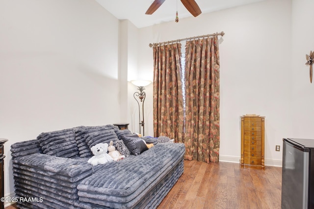 bedroom with freestanding refrigerator, wood finished floors, a ceiling fan, and baseboards