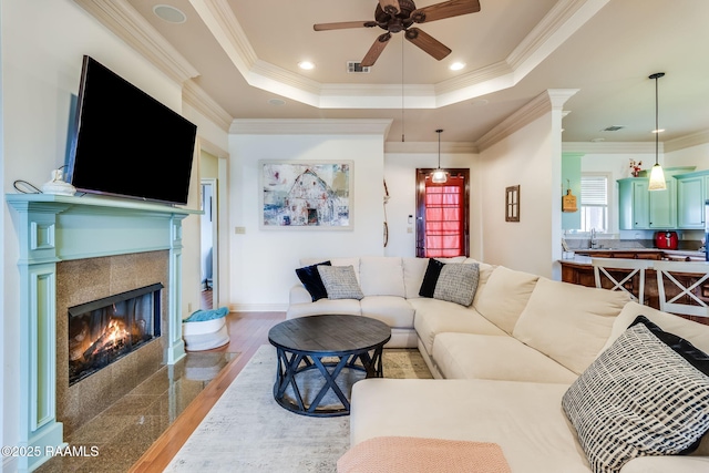 110 Beringer Dr, Duson, LA 70529 - living area with crown molding, a tiled fireplace, a ceiling fan, a tray ceiling, and visible vents