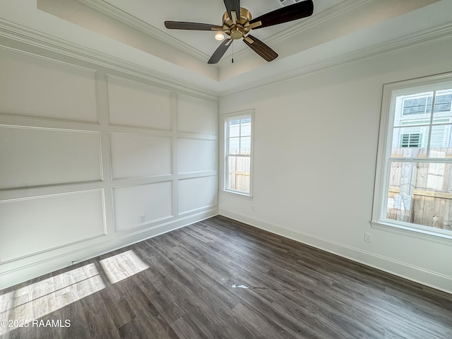 unfurnished room featuring a ceiling fan, dark wood finished floors, baseboards, ornamental molding, and a tray ceiling
