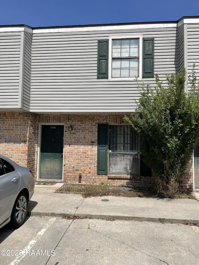 townhome / multi-family property featuring uncovered parking and brick siding