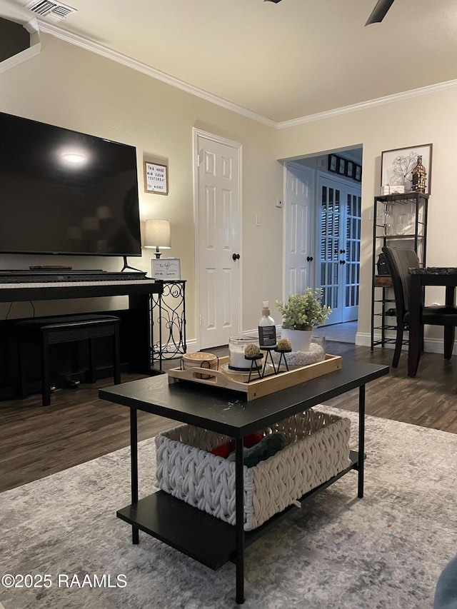 living room featuring wood finished floors, baseboards, and ornamental molding