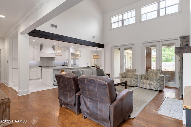 6 Oak Pl, New Iberia, LA 70563 - living area featuring visible vents, ornamental molding, an inviting chandelier, a towering ceiling, and light wood-style flooring
