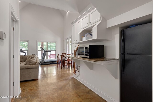 6 Oak Pl, New Iberia, LA 70563 - kitchen featuring open shelves, concrete flooring, freestanding refrigerator, dark stone counters, and white cabinetry