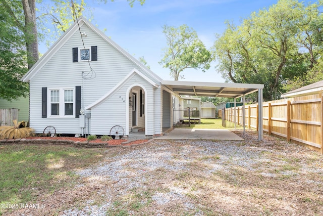 view of front facade with fence, an outbuilding, an attached carport, and a storage shed