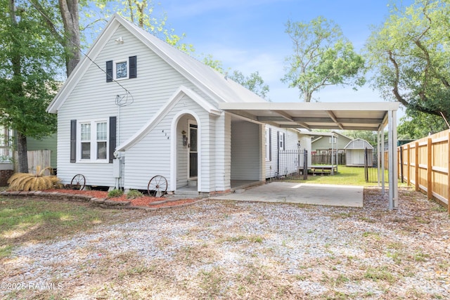 view of front facade with fence, driveway, a storage shed, an outbuilding, and a carport