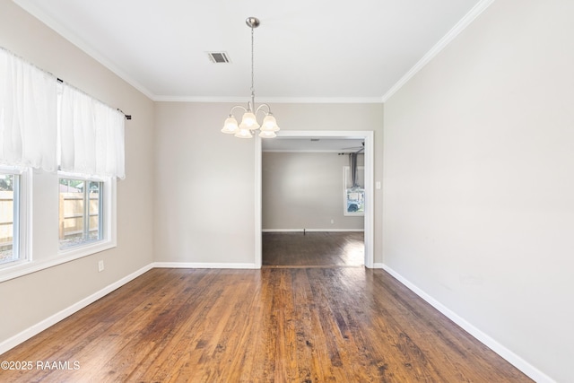 empty room with visible vents, crown molding, wood finished floors, and a notable chandelier