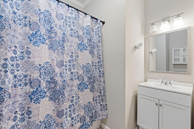 bathroom with crown molding, baseboards, a shower with shower curtain, and vanity