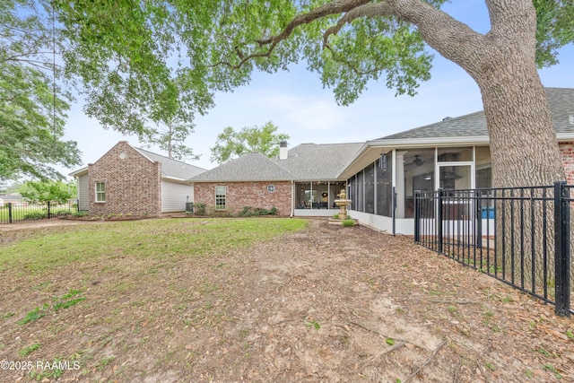 back of house with fence private yard, a sunroom, a ceiling fan, a shingled roof, and a lawn