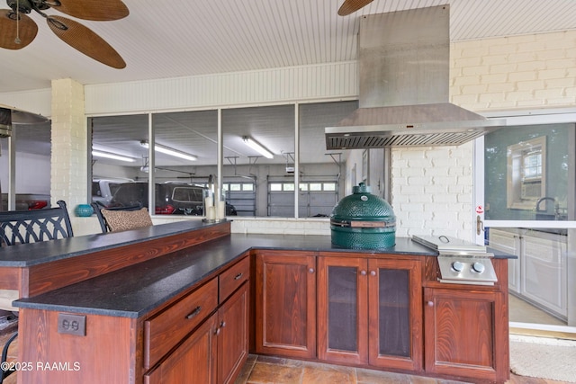 kitchen with exhaust hood, dark brown cabinets, ceiling fan, and glass insert cabinets