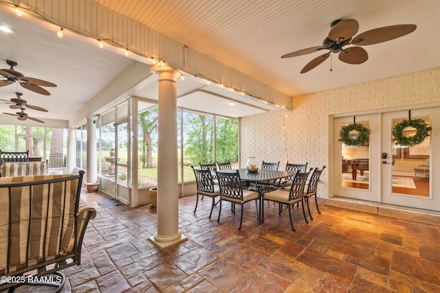 sunroom / solarium featuring stone tile floors, brick wall, and french doors