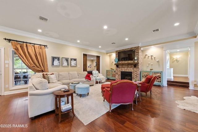 living area with visible vents, ornamental molding, wood-type flooring, and a fireplace