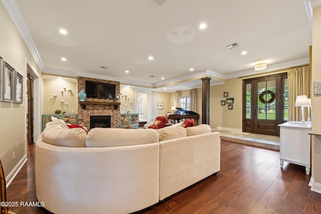 living room featuring crown molding, decorative columns, visible vents, and a wealth of natural light