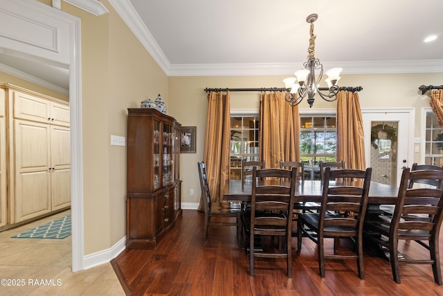 dining area featuring baseboards, ornamental molding, wood finished floors, and a notable chandelier