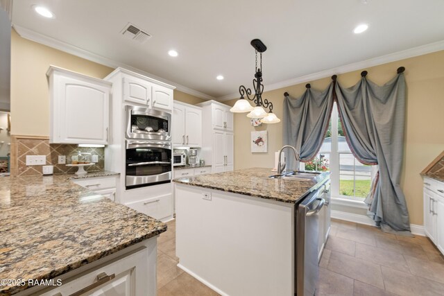 kitchen with appliances with stainless steel finishes, a sink, white cabinetry, visible vents, and ornamental molding