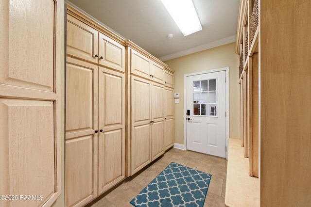 mudroom with crown molding and light tile patterned flooring