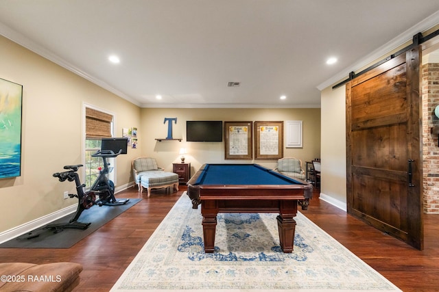 recreation room with baseboards, ornamental molding, a barn door, and wood finished floors