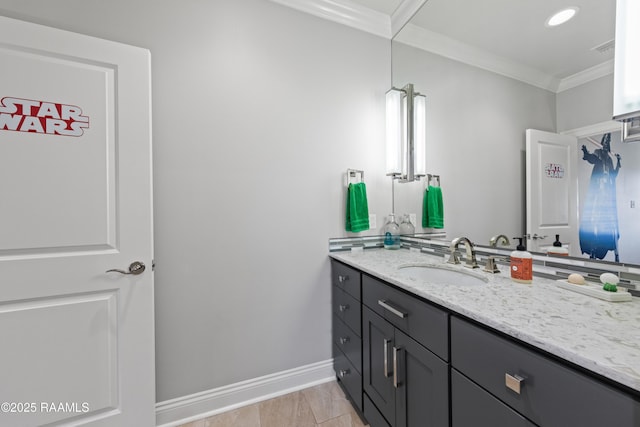 bathroom with vanity, ornamental molding, and baseboards