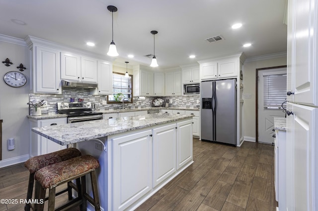 kitchen with stainless steel appliances, a kitchen island, decorative backsplash, and white cabinets