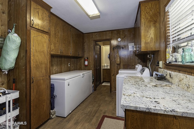 laundry area with a sink, wood walls, cabinet space, washing machine and clothes dryer, and dark wood-style floors