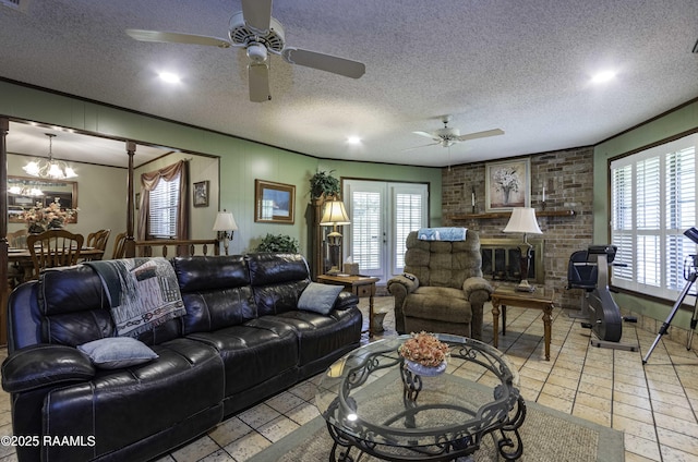 living area featuring a textured ceiling, a brick fireplace, ceiling fan with notable chandelier, and recessed lighting
