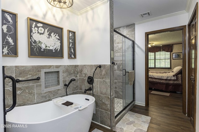 ensuite bathroom with connected bathroom, a stall shower, tile walls, visible vents, and ornamental molding