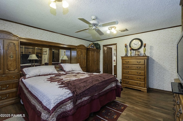 bedroom featuring crown molding, dark wood finished floors, visible vents, and a textured ceiling