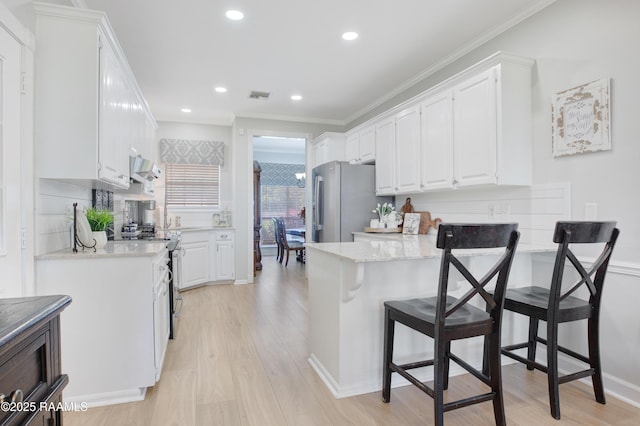 502 River Woods Dr, Lafayette, LA 70508 - kitchen with stainless steel appliances, a peninsula, white cabinets, crown molding, and light wood finished floors