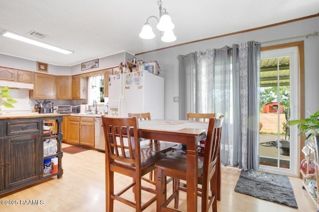 dining room with ornamental molding, visible vents, a toaster, an inviting chandelier, and light wood-style floors