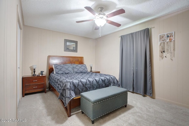 bedroom featuring a textured ceiling, carpet, a decorative wall, and a ceiling fan
