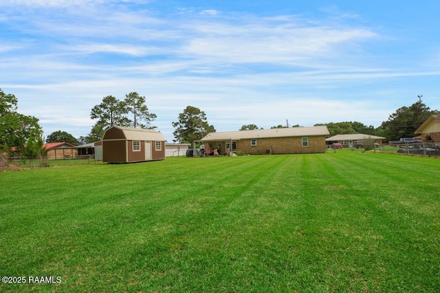 view of yard with fence, a storage shed, and an outbuilding