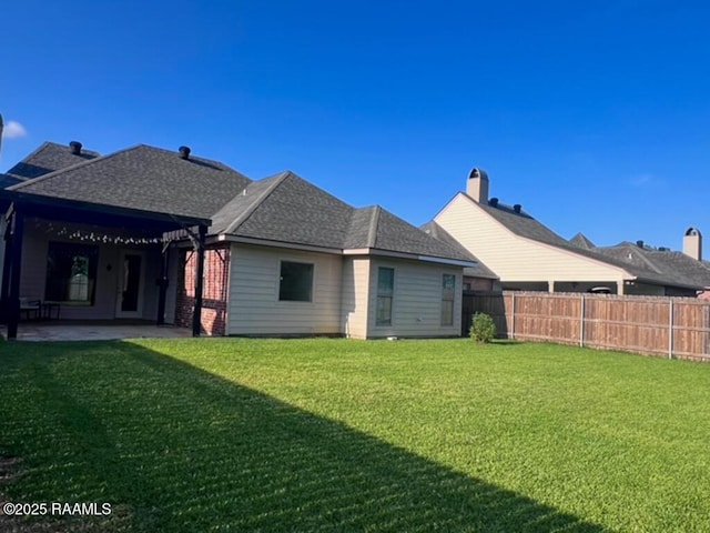 204 Red Cedar Ln, Youngsville, LA 70592 - rear view of house with a lawn, a patio, a fenced backyard, and roof with shingles