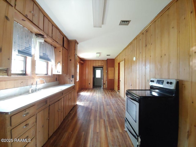 kitchen with wooden walls, electric range, a sink, dark wood-type flooring, and visible vents