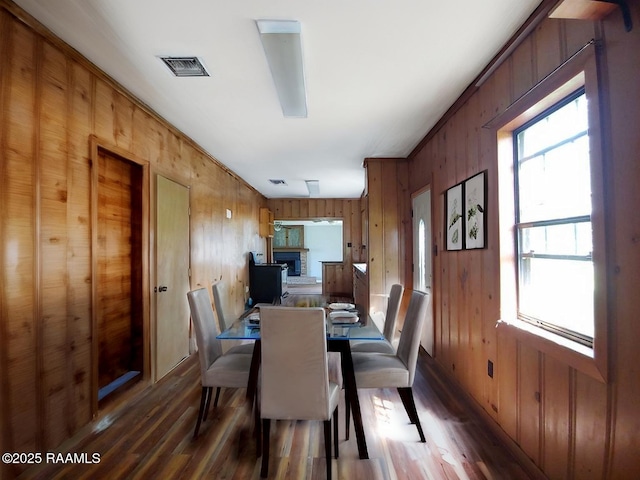 dining space featuring wooden walls, visible vents, wood finished floors, and a wealth of natural light