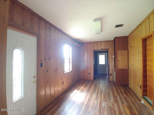 foyer entrance with visible vents, wood walls, and light wood finished floors